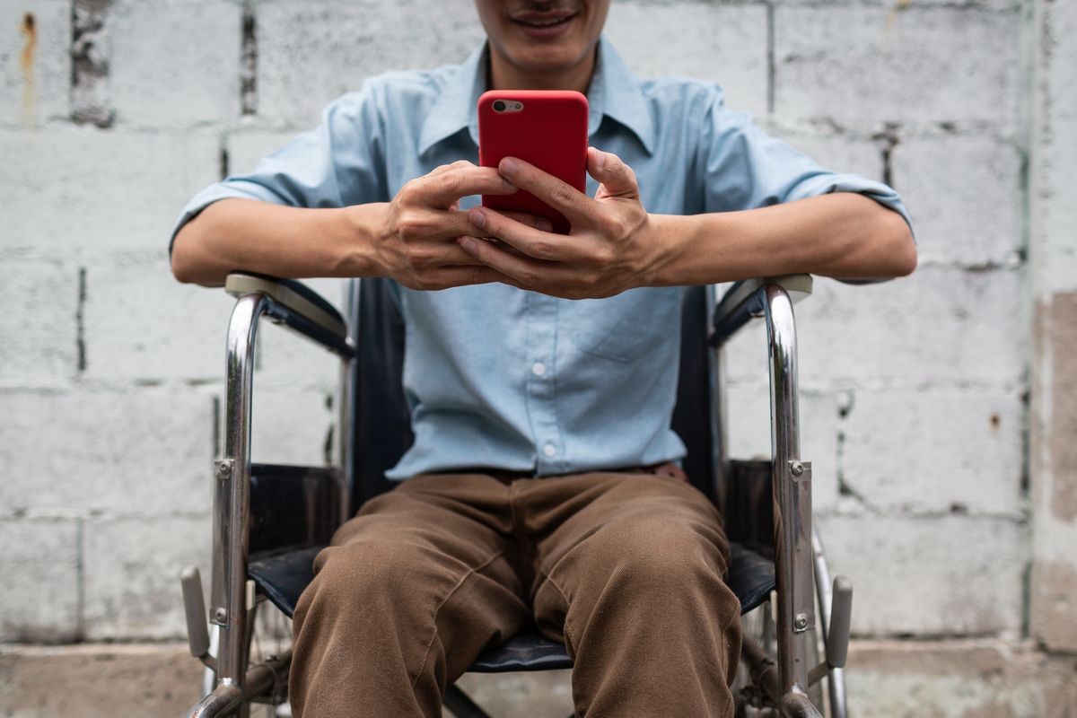 Young man on wheelchair happy with mobile phone application, Disabled concept.